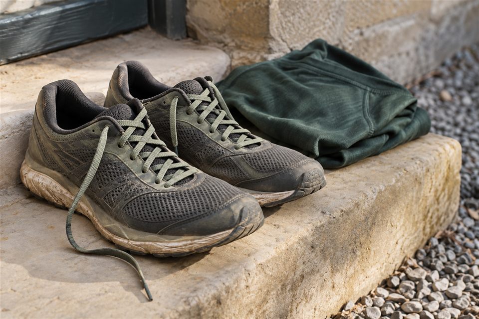 Worn running shoes with loose laces on a doorstep, ready for another run.